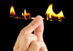 Hand holding a match burning at both ends